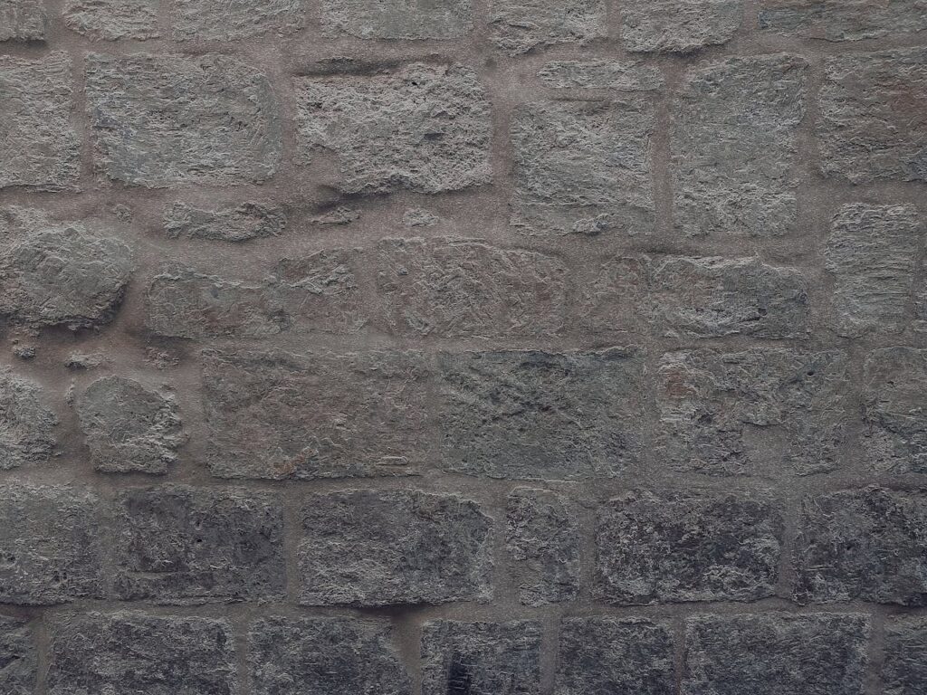 A detailed view of a rugged gray stone wall, showcasing its texture and pattern.